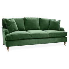 a green velvet couch with four pillows on it's arms and legs, against a white background