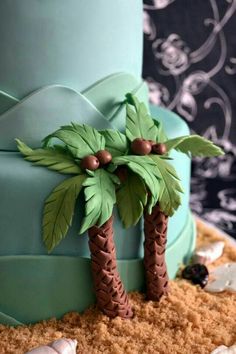 a blue cake decorated with palm trees and seashells