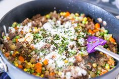 a pot filled with meat and vegetables on top of a stove next to a purple spatula