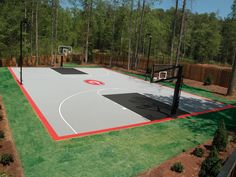 an outdoor basketball court surrounded by trees and grass