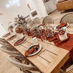 a wooden table topped with lots of plates and place settings