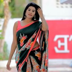 a woman in a sari walking down the street with her hand on her head