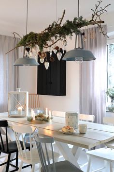 a dining room table and chairs with lights hanging from the ceiling