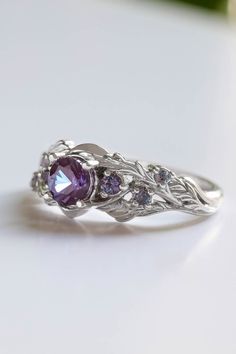 a white gold ring with an amethorate and purple stones