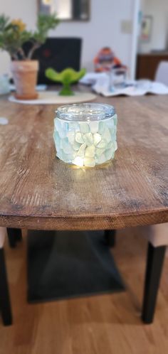 a glass jar filled with white pebbles on top of a wooden table