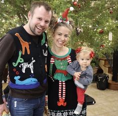 a man and woman standing next to each other in front of a christmas tree