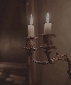 two candles are lit on a candle holder