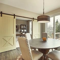 a dining room table with chairs and a bowl of fruit on it