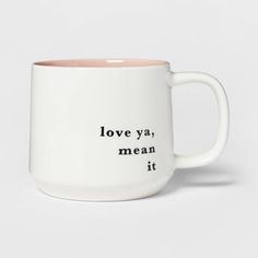 a white and pink coffee mug with the words love ya mean it in black lettering