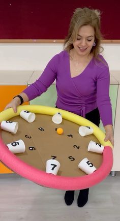 a woman holding a giant game board with numbers on it