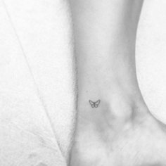 a small butterfly tattoo on the ankle is shown in this black and white photo,