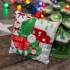 a christmas pillow sitting on top of a wooden table next to a small christmas tree