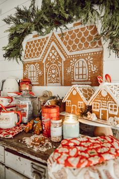 gingerbread houses are displayed on a kitchen counter with christmas decorations and other holiday items