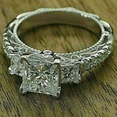 three stone princess cut diamond engagement ring with filigrees on the band and side stones