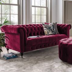 a red velvet couch and ottoman in a living room