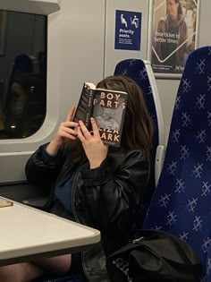 a woman sitting on a train reading a book