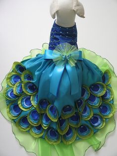 a stuffed animal wearing a blue and green dress with peacock feathers on it's skirt