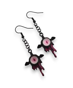 two black and pink earrings with chains hanging from the ear hooks, one has an evil face on it