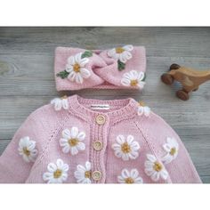 a pink sweater and hat with white flowers on it