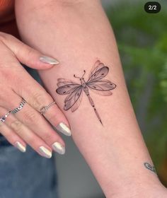 a woman's arm with a small dragonfly tattoo on the left side of her arm