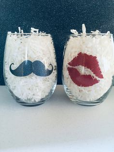 two wine glasses decorated with red lips and moustaches are sitting next to each other