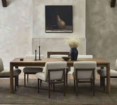 a dining room table with chairs and a vase on the table in front of it