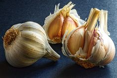 three bulbs of garlic sitting next to each other on a blue counter top with one bulb opened