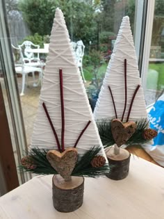 two white christmas trees sitting on top of a wooden table