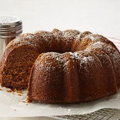 a bundt cake with powdered sugar on top sits on a cooling rack next to a salt shaker