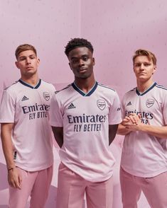 three soccer players in pink uniforms posing for the camera with their hands on their chest