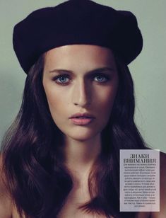 a woman with long hair wearing a black beret and posing for a magazine cover