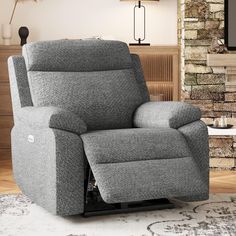 a grey recliner chair sitting in front of a brick wall with a tv on top of it