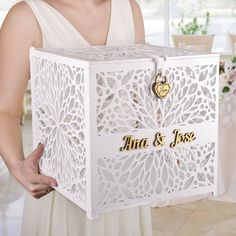 a woman in a white dress is holding a wedding card box