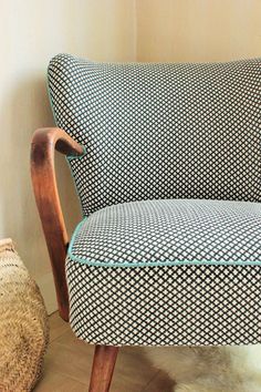 a blue and white patterned couch sitting on top of a hard wood floor next to a basket