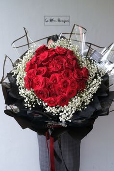 a man holding a large bouquet of red roses