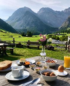 an outdoor table with food and drinks on it in the middle of a grassy field