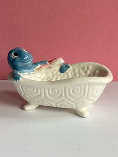 a ceramic blue turtle sitting in a bathtub with a toothbrush on it's head