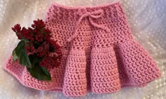 a pink crocheted skirt and flower on a bed