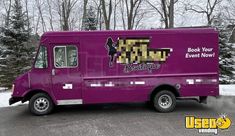 a purple food truck parked on the side of a road with trees in the background