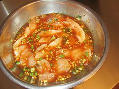 a metal bowl filled with food on top of a stove burner covered in sauce