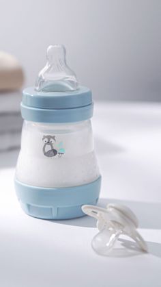 a blue and white baby bottle sitting on top of a table next to a pacifier