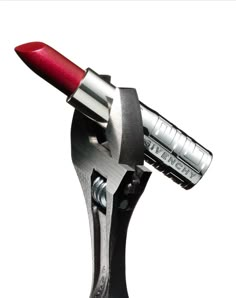 a close up of a red lipstick on a metal object with a white back ground