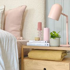 a nightstand with two books and a pink lamp