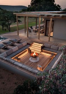 a fire pit in the middle of a deck with couches and tables around it