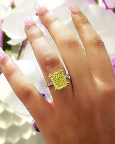 a woman's hand with a yellow and white diamond ring on top of it