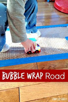 a child is playing with a toy truck on the floor and text reads bubble wrap road