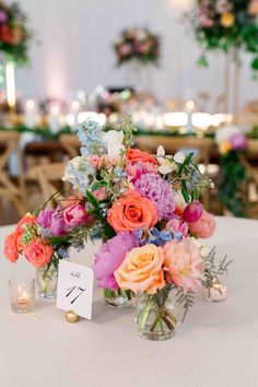 a vase filled with lots of colorful flowers on top of a white table covered in candles