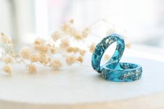 two blue rings sitting on top of a table next to some dried flowers and a window