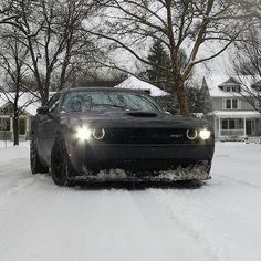 a black car driving down a snow covered road