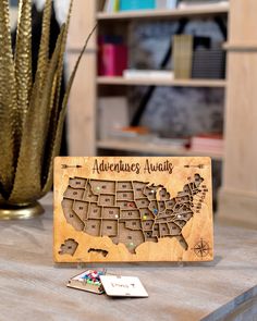 a wooden sign with the map of the united states on it sitting on a table next to a potted plant